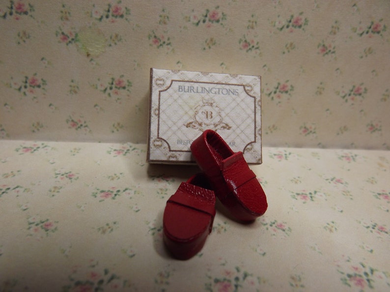 May include: Two red leather loafers with a box that says "Burlintgton's" on it.