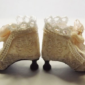 May include: A pair of white satin shoes with lace trim and pink bows. The shoes have a delicate design and are perfect for a special occasion.