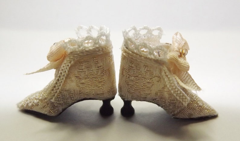 May include: A pair of white satin shoes with lace trim and pink bows. The shoes have a delicate design and are perfect for a special occasion.