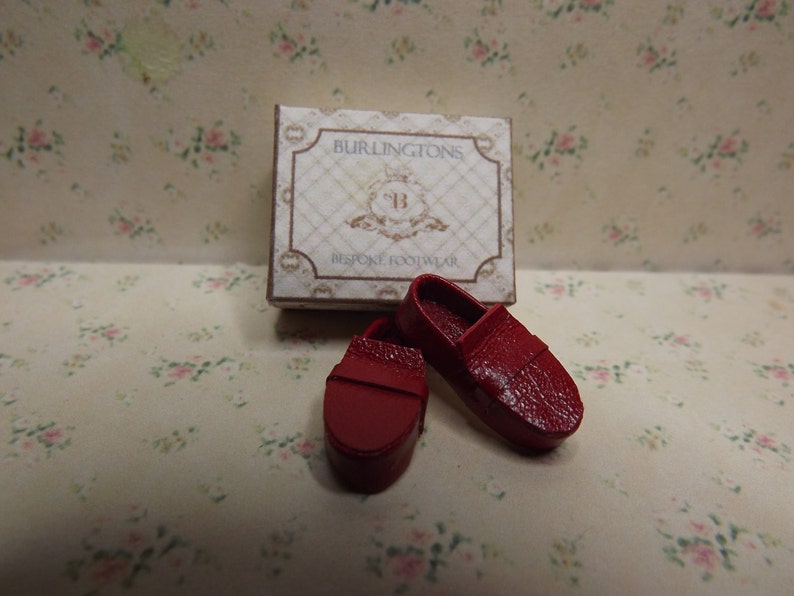 May include: Two miniature red leather shoes in a box that says "Burlintons Bespoke Footwear".