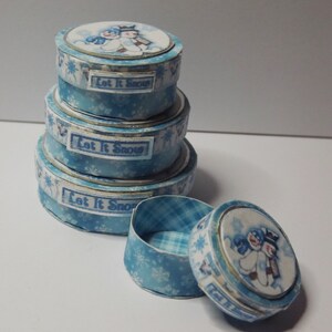 May include: Set of four blue and white paper gift boxes with a snowman design and the text "Let It Snow".