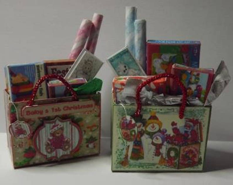 May include: Two decorated gift bags filled with wrapped gifts, books, and wrapping paper. The bags are decorated with Christmas themes and the text "Baby's 1st Christmas".