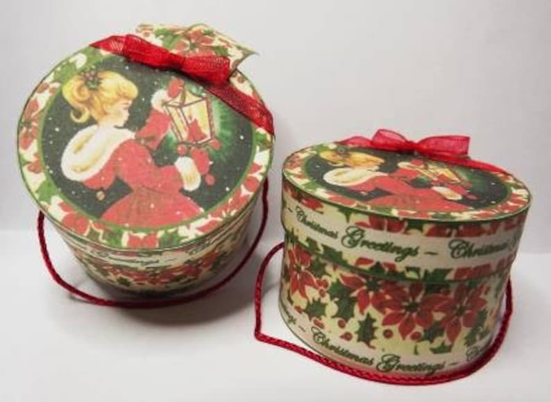 May include: Two round Christmas gift boxes with red ribbon bows and a vintage Christmas scene printed on the sides. The boxes have a white background with red and green holly and poinsettia designs. The text on the boxes reads "Christmas Greetings".