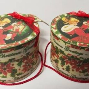 May include: Two round Christmas gift boxes with red ribbon bows and a white background with a green and red floral pattern. The boxes have the text "Christmas Greetings" on them.