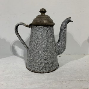 May include: Vintage speckled enamelware coffee pot with a metal lid and handle. The pot has a gray and white speckled pattern and a curved spout. The handle is curved and attached to the side of the pot. The lid has a small knob on top.
