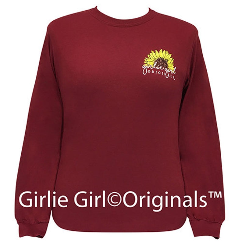 May include: Burgundy long-sleeve shirt with a sunflower graphic and the text "Girlie Girl Originals" in white.