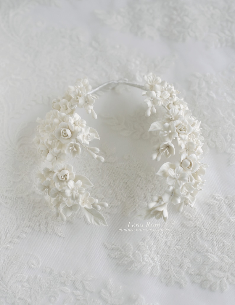 May include: White floral hair comb with delicate white flowers and leaves. The comb is made of porcelain and is perfect for a wedding or special occasion.