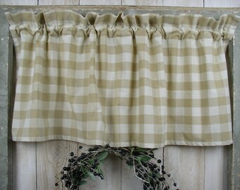 May include: A tan and white gingham valance with a ruffled top edge. The valance is hanging on a window with a wooden frame.
