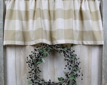 May include: A tan and white gingham valance with ruffles hangs above a wreath made of twigs and black berries.