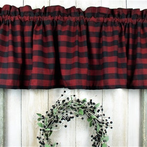 May include: Red and black buffalo plaid valance with a gathered ruffle top. The valance is made of a soft, woven fabric and is perfect for adding a touch of rustic charm to any window.