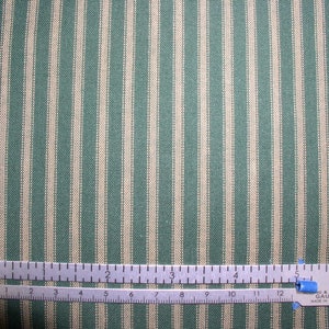 May include: A close-up of a green and white striped fabric with a ruler measuring 5 inches. The fabric has a subtle texture and a classic striped pattern.
