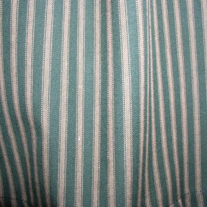 May include: Close-up of a fabric with alternating teal and white stripes. The fabric has a woven texture.