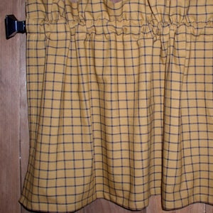 May include: A yellow and black checkered valance with a gathered top and a scalloped bottom.