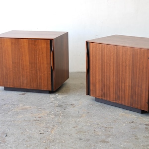 May include: Two wooden nightstands with a single door each. The nightstands are made of dark wood with a smooth finish. The doors have a unique curved design.