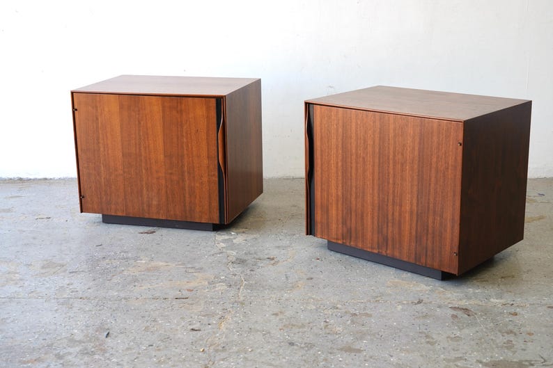May include: Two wooden nightstands with a single door each. The nightstands are made of dark wood with a smooth finish. The doors have a unique curved design.