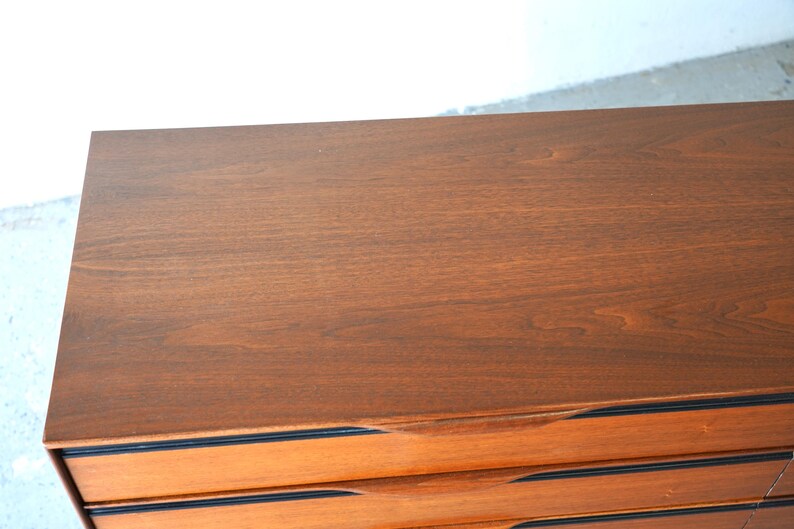 May include: A wooden dresser with six drawers. The top drawer is closed and the rest are open. The dresser has black trim around the drawers.