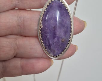 Polished Amethyst Cabochon Pendant. Lacy silver bezel.  Silver snake chain necklace.