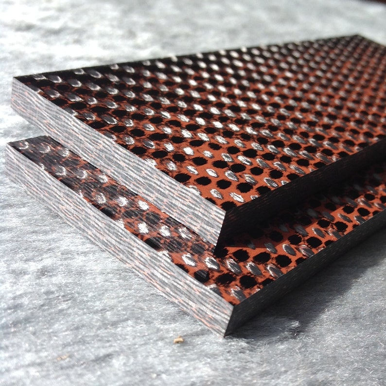 May include: Two pieces of black and brown patterned wood with a white dot pattern. The wood is stacked on top of each other.