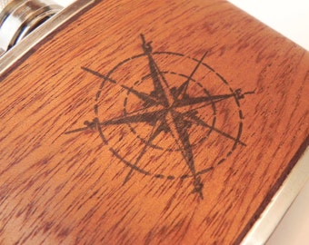 May include: A wooden flask with a compass design engraved on the front. The flask is made of dark wood with a silver trim.
