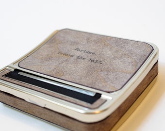 May include: A wooden and metal rolling tray with a silver trim. The top of the tray is covered in a brown suede-like material with the words "Fortune favors the bold." engraved on it.