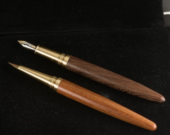 May include: Two wooden pens with gold accents. The pen on the left has a dark brown wood finish and a fine nib. The pen on the right has a lighter brown wood finish and a brush tip.