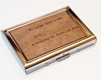May include: A silver metal card case with a wooden insert. The wood has the text "He walks like a man with a destiny in front of him." engraved on it.