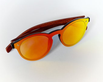May include: A pair of round sunglasses with a brown wooden frame and orange mirrored lenses.