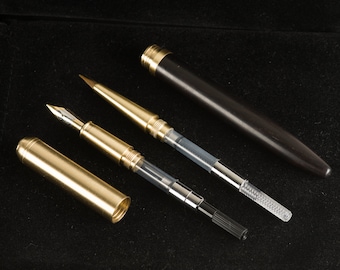 May include: Three writing instruments, including a black fountain pen, a gold-colored pen with a clear barrel, and a gold-colored pen with a black barrel and a clear tip.