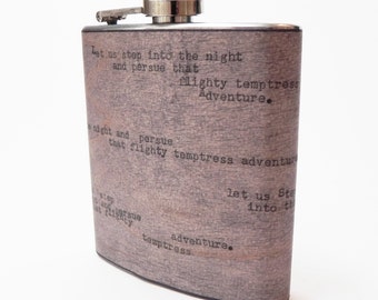 May include: A stainless steel flask with a wood-grain finish and a quote from a poem engraved on the side: "Let us step into the night and pursue that flighty temptress Adventure."