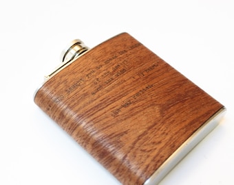 May include: A brown wood-grain flask with a silver lid and engraved text: "To laughter, you to work, you to love, you to the end, you to the stars, and to the dream of it all, I my heart, Live well, rest well."