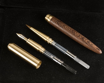 May include: Three gold-toned pens with a wooden pen on a black surface. The wooden pen has a dark brown wood grain pattern. The gold pens have clear plastic barrels and are disassembled.