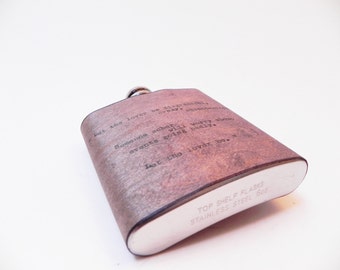 May include: A brown leather flask with a silver top and a quote engraved on the front: "Let the lover be... Someone saber events going badly. Let the lover be."