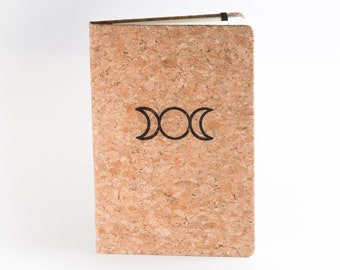 May include: A cork notebook with a triple moon symbol printed on the front cover.