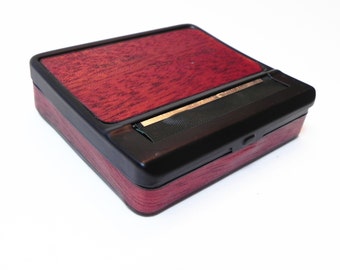 May include: A wooden rolling tray with a black plastic lid and a built-in rolling mechanism. The tray has a dark red wood grain pattern.