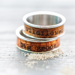 May include: Two wooden rings with silver bands. The top ring has the words "Wildflower" engraved on it. The bottom ring has the words "Big Spoon" engraved on it.