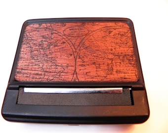 May include: A black rolling tobacco case with a wood-grain design featuring a world map and the text "WORLD".