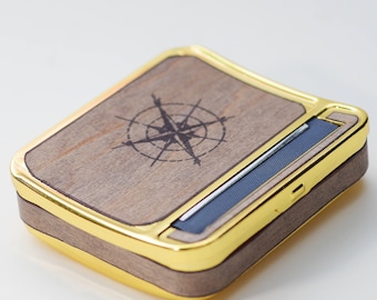May include: A wooden rolling tray with a gold trim and a compass design. The tray has a built-in rolling machine with a blue plastic blade.