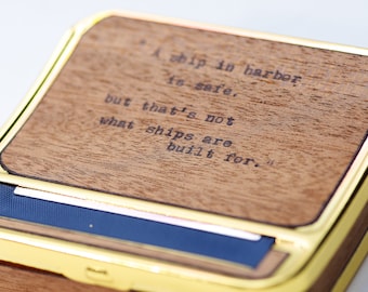 May include: A wooden rolling tray with a gold trim and a quote engraved on the top: "A ship in harbor is safe, but that's not what ships are built for."