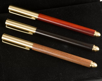May include: Three pens with gold accents and different wood finishes: a dark red pen, a black pen, and a brown pen.