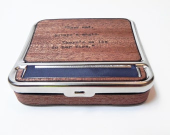 May include: A wooden rolling tray with a silver metal trim. The tray has a quote engraved on the top: "She's mad, but she's magic. There's no lie in her fire."