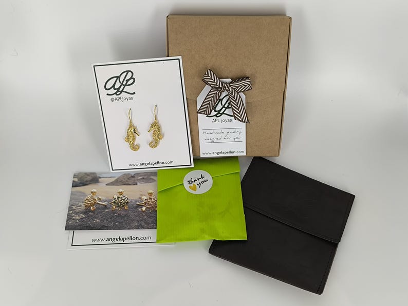 May include: A brown cardboard box with a green gift bag and a thank you sticker. The box has a tag that says "AP Joyas Handmade jewelry designed for you www.angelapellon.com". The gift bag has a sticker that says "Thank you".