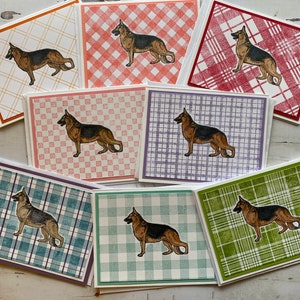 May include: Eight cards with a German Shepherd dog illustration on each. The cards have different plaid patterns in red, green, blue, purple, and white.