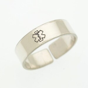 May include: A silver ring with a medical symbol engraved on it.