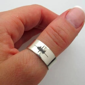 Può includere: Un anello d'argento con un design a onda sonora inciso sulla fascia.