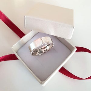 May include: A silver ring with the words "Type 2 Diabetes Asthma" engraved on the inside of the band. The ring is in a white box with a red ribbon.