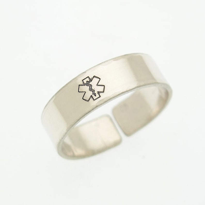 May include: A silver ring with a medical symbol engraved on it.