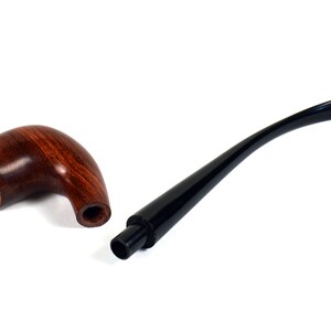 May include: A wooden pipe with a brown finish and a black stem. The pipe is disassembled, showing the bowl and the stem separately.