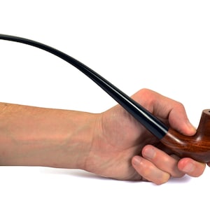 May include: A brown wooden smoking pipe with a black stem held in a hand. The pipe has a carved design on the bowl.