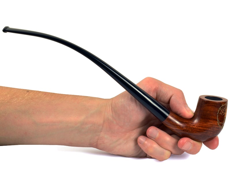May include: A brown wooden smoking pipe with a black stem held in a hand. The pipe has a carved design on the bowl.