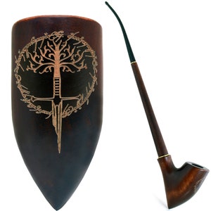 Puede incluir: Una pipa de madera marrón oscuro con un tallo largo y delgado y una boquilla negra. La pipa está decorada con una talla de un árbol y una espada, rodeada de un círculo de texto. La pipa se muestra sobre un fondo blanco.